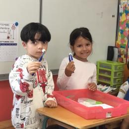 attraper des boules de cotillons avec des pinces d'infirmières et les mettre dans des alvéoles d'un bac à glaçons