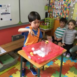 attraper des balles de ping-pong à l'aide de pinces à biberons et les faire entrer dans des cylindres