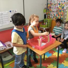 attraper des pailles avec des pinces à sucre et les passer d'un cylindre à l'autre